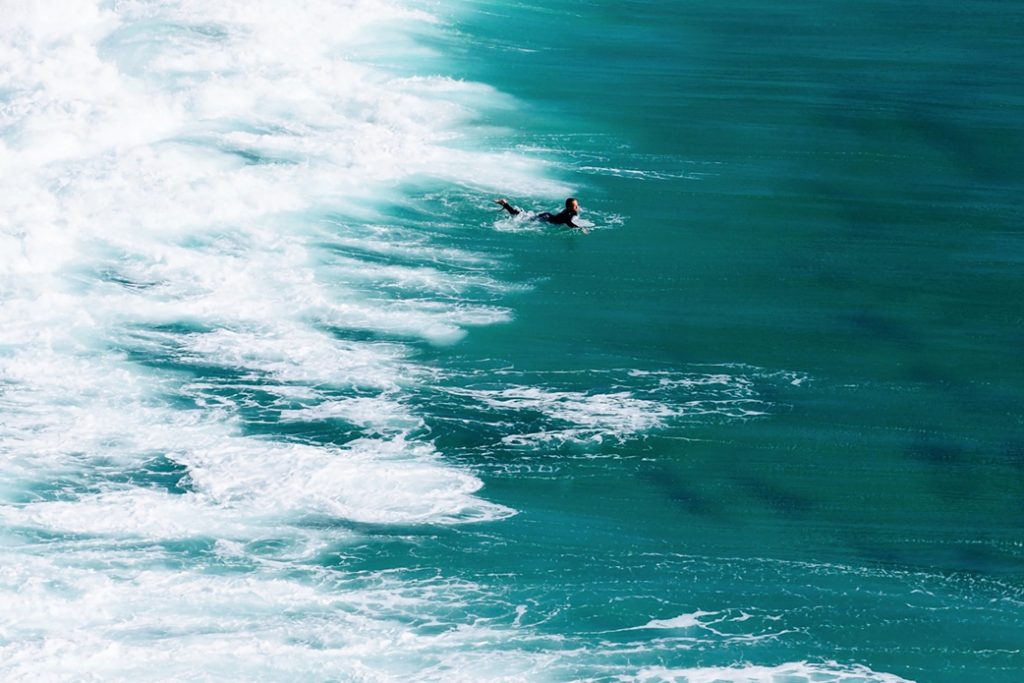 Someone paddling out on a surf board in the ocean.